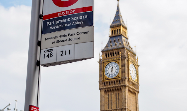 A bus srtop in Parliament SQuare in London showing that the number 148 and 211 buses stop there. In the background is Big Ben.