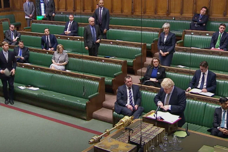 Wide view of Boris Johnson speaking in a mostly empty Commons Chamber with a smattering of MPs sitting in the green benches behind him
