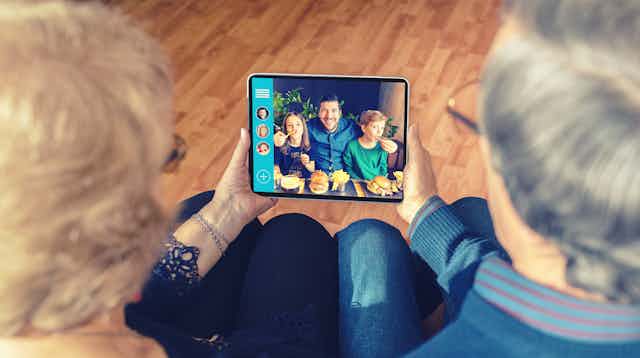 Senior couple hold a tablet for a video call with child and grandchildren
