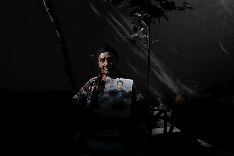 A woman hold a photograph of a young man.