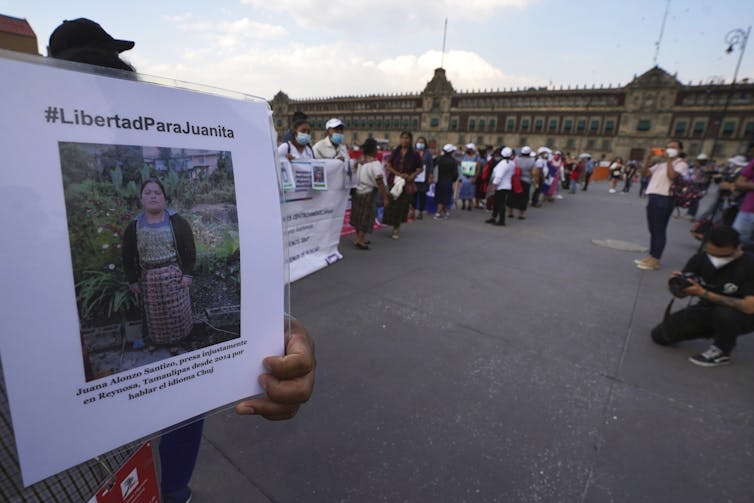 People hold up signs of their missing loves ones in a city square.