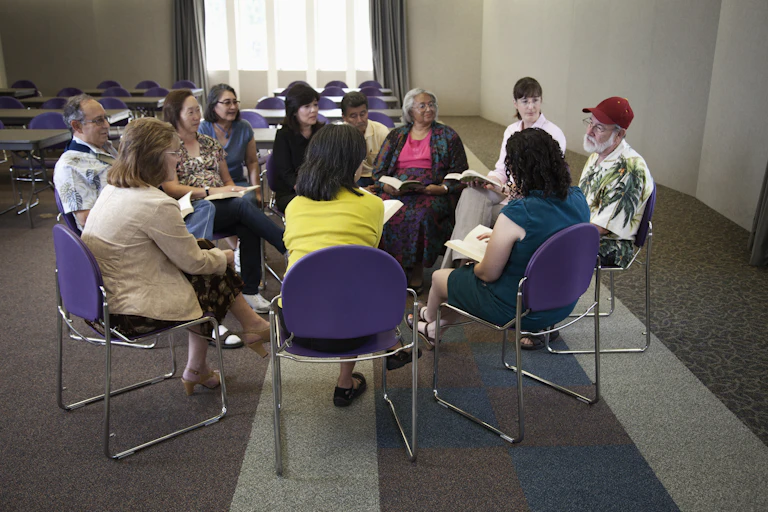 People sitting in a circle and having a discussion around a book.