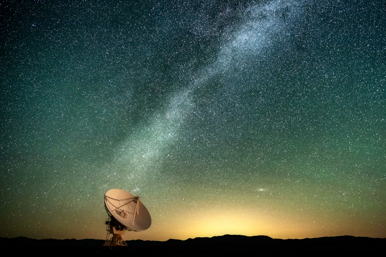 A large telescope against the backdrop of the Milky Way in the sky.