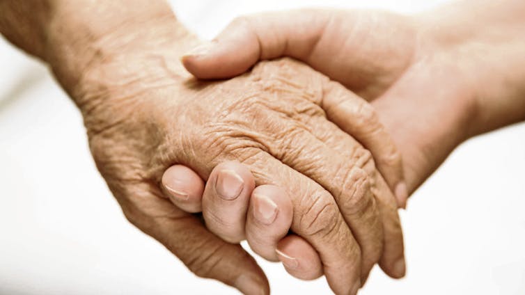 Close-up of younger person holding hand of older person