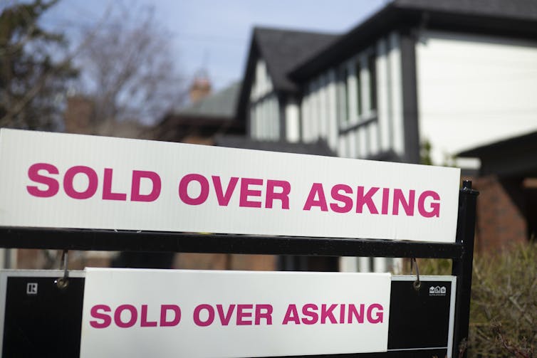 A sign that reads 'sold over asking' is plastered in front of a home