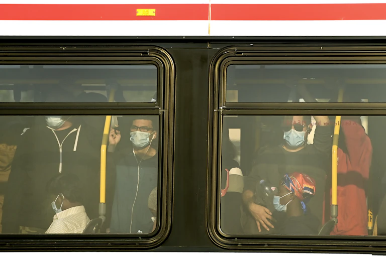 Commuters crowded together, seen through bus windows