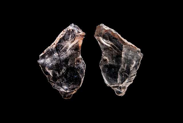 Photograph of two stone tools against a black background.