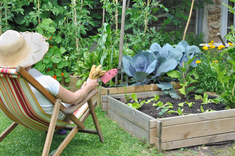 woman in hat sits and looks over garden