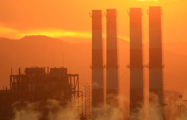 Four power plant smokestacks at sunset