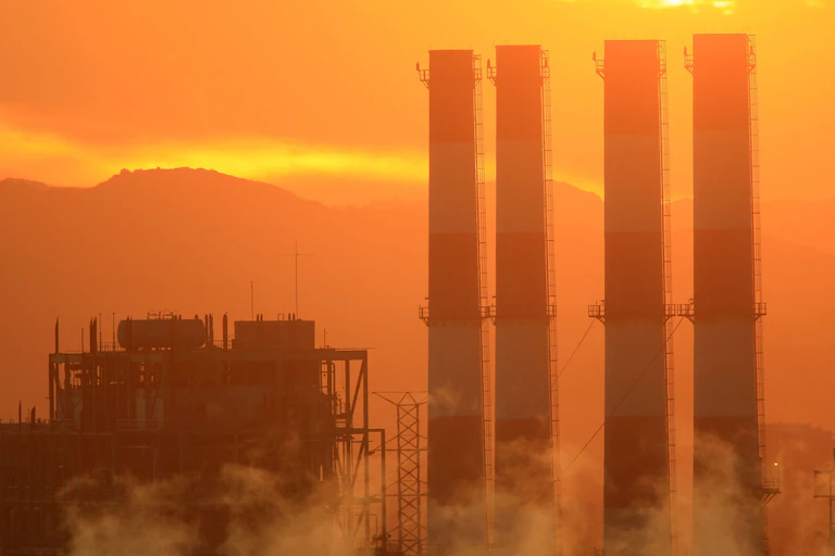 Four power plant smokestacks at sunset