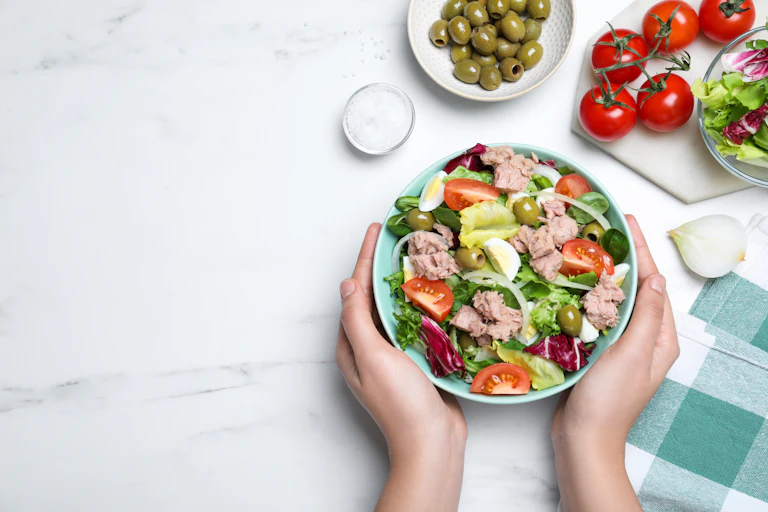 Hand holds a bowl of tuna salad.