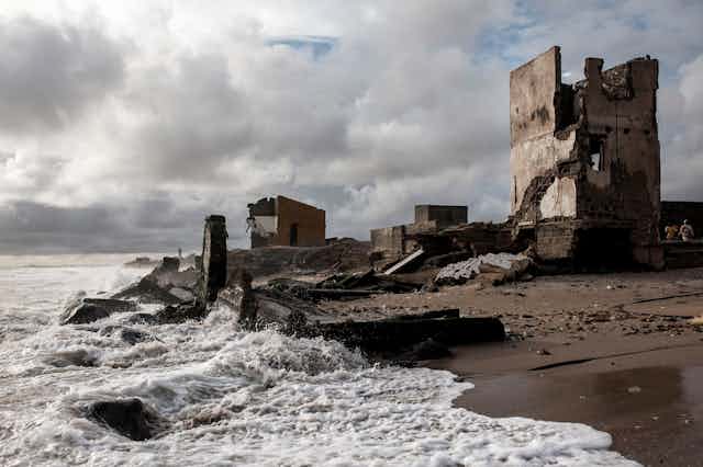 El mar golpea los edificios destruidos en una playa
