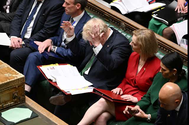 View from above of Boris Johnson throwing his hands in the air while sitting in PMQs with ministers at his sides