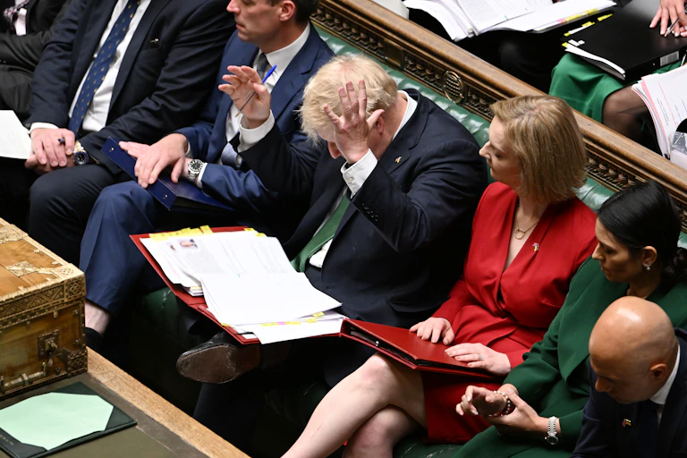 View from above of Boris Johnson throwing his hands in the air while sitting in PMQs with ministers at his sides
