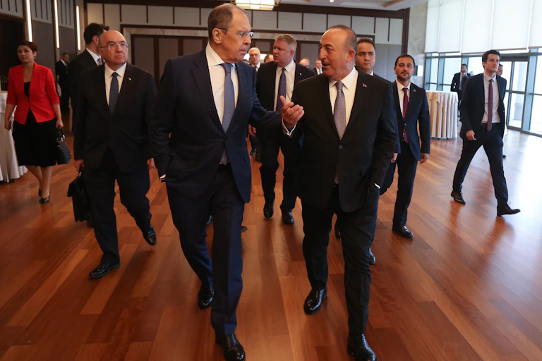 Group of men and women in suits walking down corridor, two talking to each other.