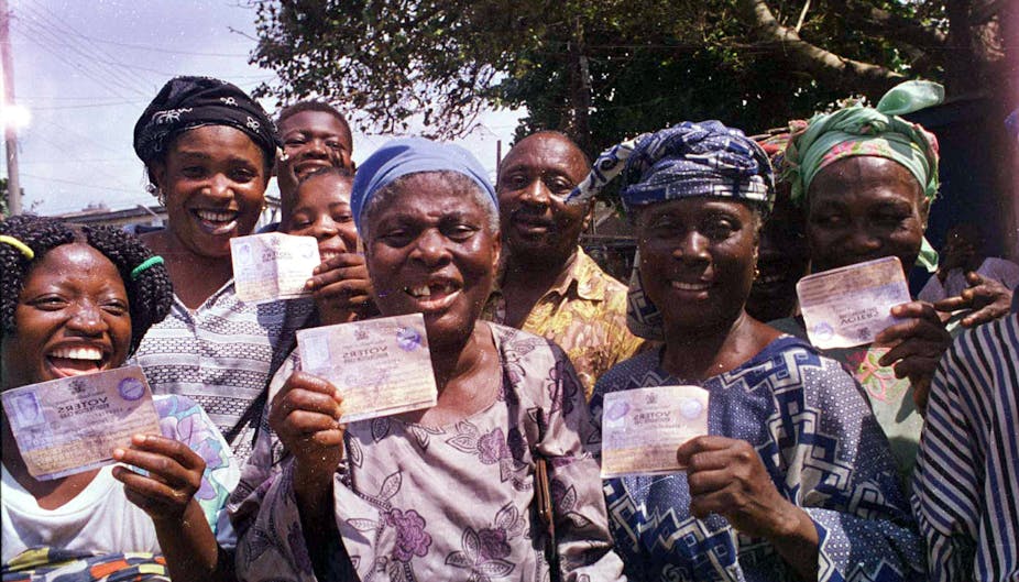 Five women holding voter cards