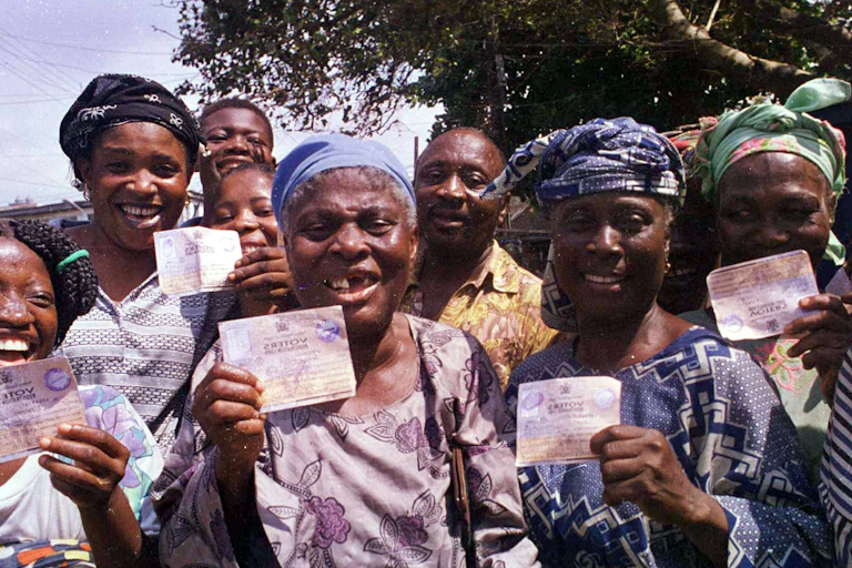 Five women holding voter cards
