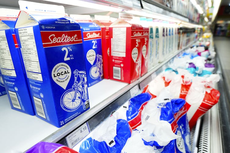 Sealtest blue and red cartons and bags of milk on grocery store shelves.