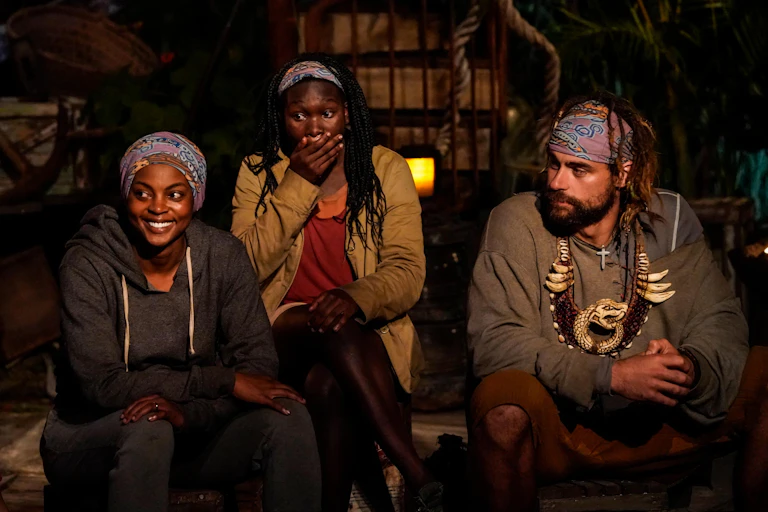 Three people sit during a tribal council