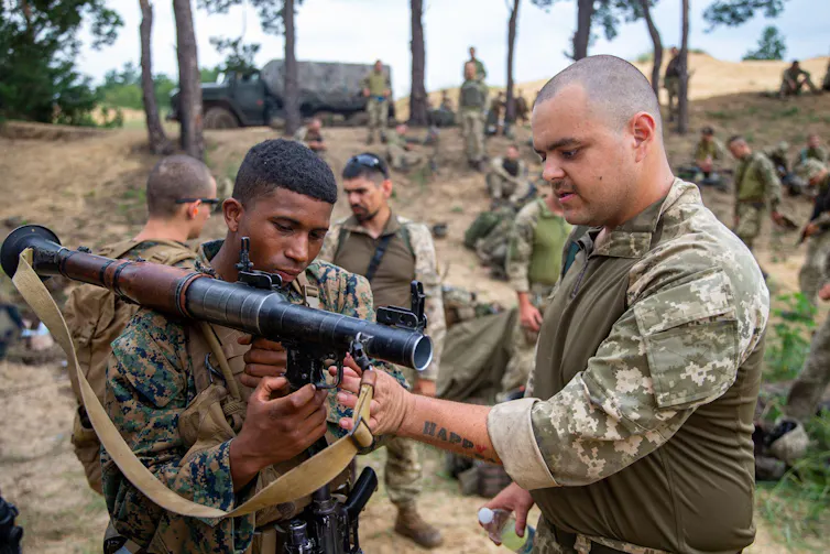Two soldiers handling an AK-74 assault rifle during military exercises in July 2021.
