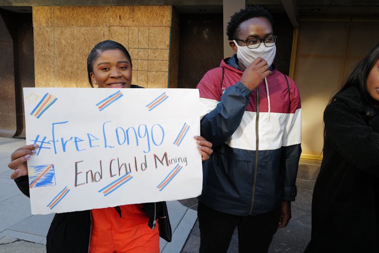 A person holds a sign reading '#FreeCongo End Child Mining'