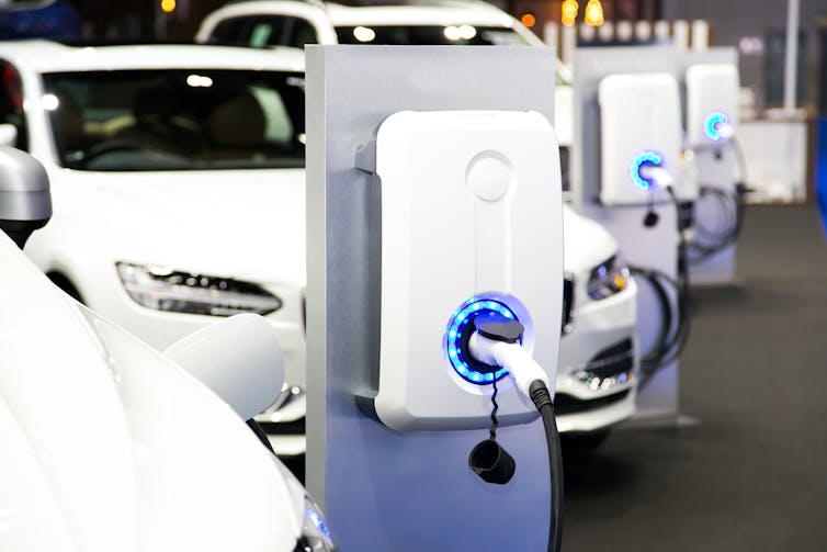 White cars charging electrically from charging points mounted on grey frames