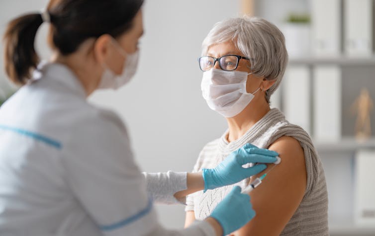 A senior woman receives a vaccine.
