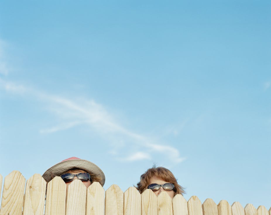 A fence with two people peeking over the top