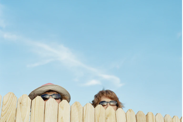 A fence with two people peeking over the top
