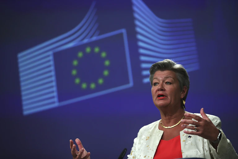 An older woman gestures with her hands as she speaks at a podium