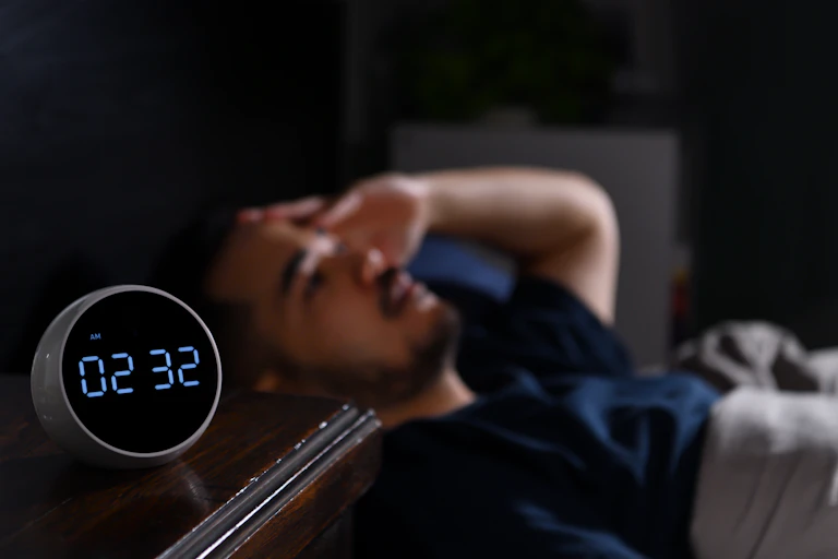 Man awake next to clock that says 02:32