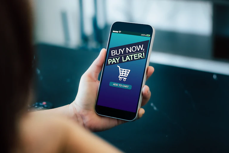 Hand holding phone with "Buy now, pay later" message.