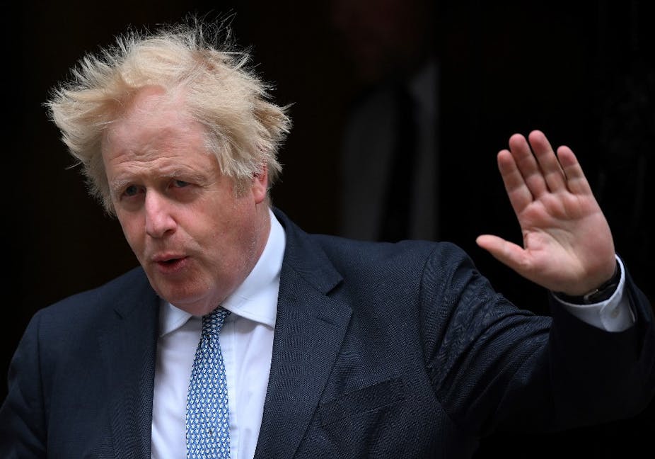 Boris Johnson, cheveux au vent, la main levée