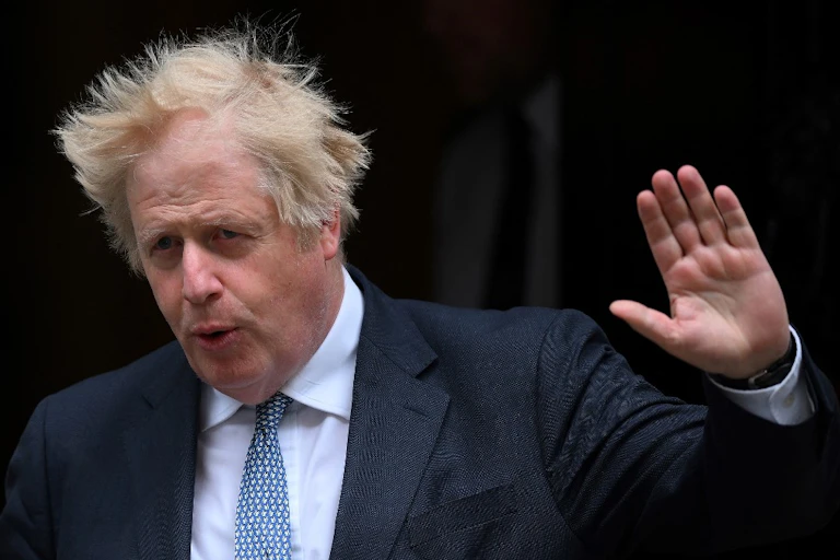 Boris Johnson, cheveux au vent, la main levée