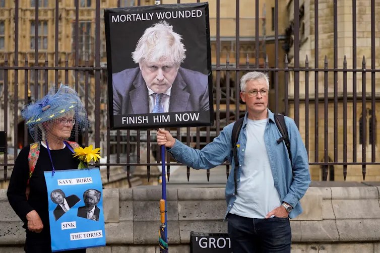 Une femme et un homme manifestent avec des slogans anti-Boris Johnson