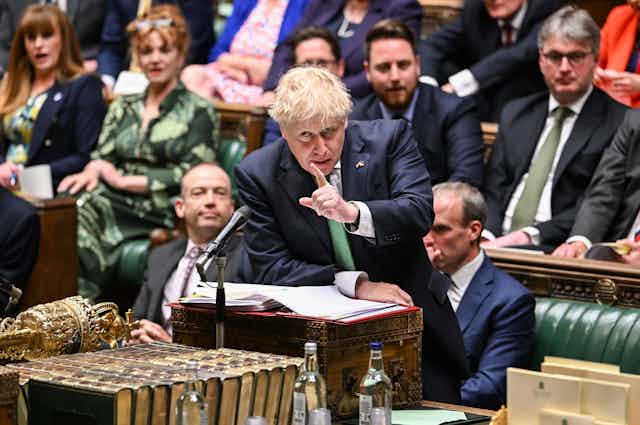 US prime minister Boris Johnson stands at the despatch box in the House of Commons, pointing at the opposition benches