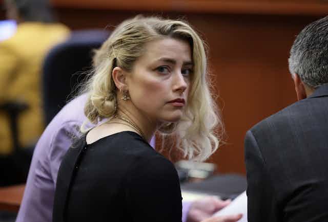 Amber Heard looks sadly over her shoulder in court