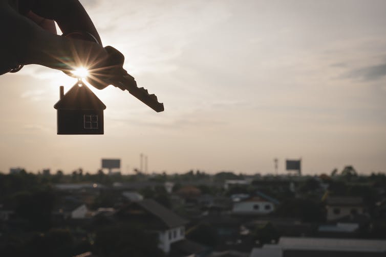 Silhouette of miniature house model with key.