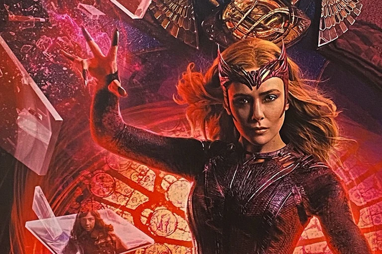 A woman superhero is seen raising one hand and intently staring against a swirling red background.