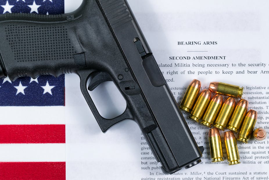 Pistolet et munitions posés sur le drapeau américain et une feuille portant le texte du deuxième amendement
