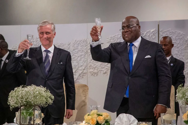 Two men hold up glasses to toast.