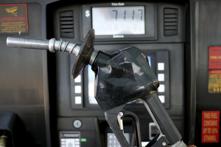A gas nozzle is held up by a pump that has the price of $71.17 listed