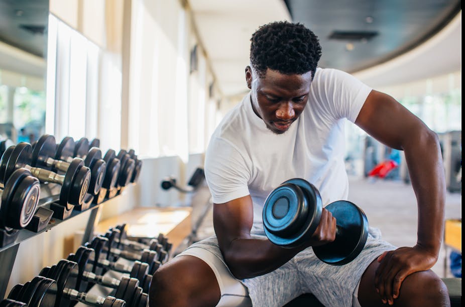 Young man performs a seated bicep curls using a dumbbell.