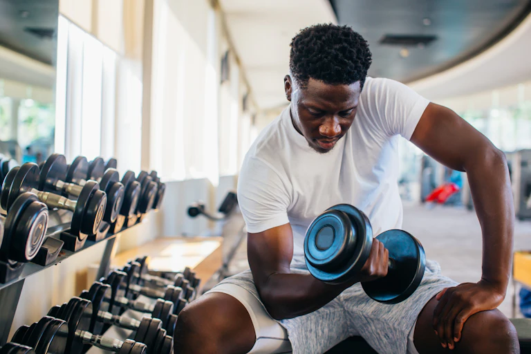 Young man performs a seated bicep curls using a dumbbell.