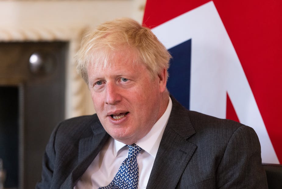 Boris Johnson sitting in front of a UK flag