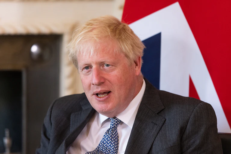 Boris Johnson sitting in front of a UK flag