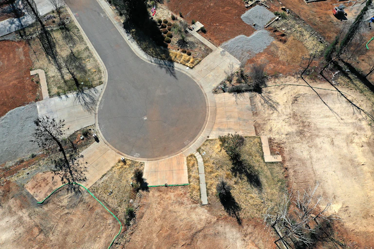 Former home lots are evident in a cul-de-sac where all that remains is the driveways and sidewalks to where homes once stood. The lots, where the homes burned, have been razed.