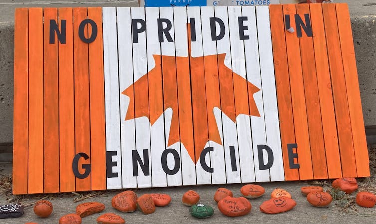 An image of an orange upside-down Canada flag reads no pride in genocide