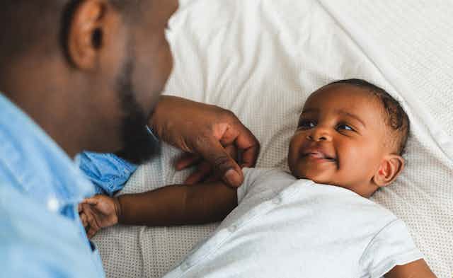 A baby seen smiling and gazing into their father's eyes.