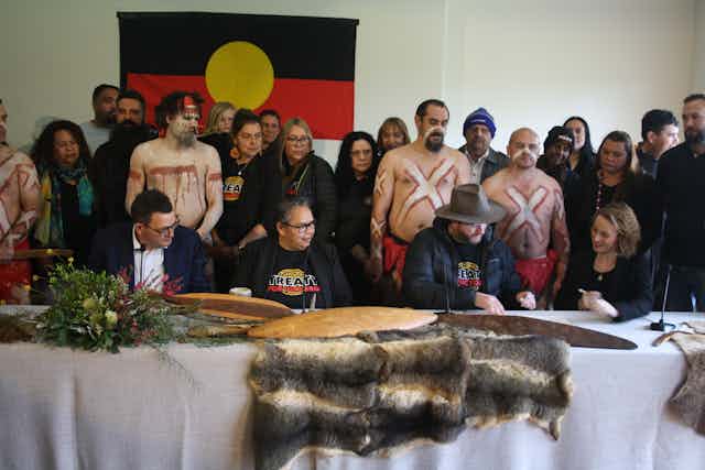 A group of people, including the Victorian First Peoples' Assembly and the Victorian Government are sitting at a long table.